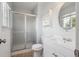 Bathroom with enclosed shower, white vanity, and round mirror over the sink at 7598 Jared Way, Littleton, CO 80125