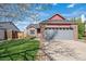 Charming brick-and-red-sided home with a well-maintained lawn, mature tree, and attached two-car garage at 7598 Jared Way, Littleton, CO 80125