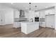 Modern kitchen with white cabinets, stainless steel appliances, a center island with pendant lighting, and wood floors at 213 Washington St, Erie, CO 80516