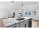 Modern kitchen with black faucet and marble countertops on the island, with a view of the dining room and entryway at 213 Washington St, Erie, CO 80516