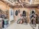 View of the tack room with saddles, saddle racks, a door to the exterior and exposed insulation at 50950 E 32Nd Ave, Bennett, CO 80102