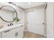 Bathroom with white vanity, black hardware, a round mirror and wood look floors at 7743 S Birch Ct, Centennial, CO 80122