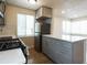 Close-up of an updated kitchen with gray cabinets, stainless steel appliances, and wood flooring at 1564 Verbena St, Denver, CO 80220