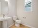 Elegant powder room featuring a pedestal sink, toilet, and a window that provides natural light at 3350 Backdrop Ct, Castle Rock, CO 80108