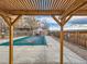 View of the community pool with a safety cover, framed by a pergola and surrounding landscaping at 1699 S Trenton St # 172, Denver, CO 80231