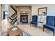 Comfortable living room boasts a stone fireplace, wood floors, and trendy blue chairs under a staircase at 1699 S Trenton St # 172, Denver, CO 80231