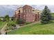 Charming condo building with lush landscaping, mature trees, and cozy benches for relaxing outdoors at 303 Inverness Way # 201, Englewood, CO 80112