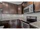 Close-up view of kitchen features dark wood cabinets, stainless steel appliances, and granite countertops at 303 Inverness Way # 201, Englewood, CO 80112