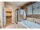 Bright bathroom featuring a soaking tub, glass-enclosed shower, and a large walk-in closet at 10968 Macon St, Commerce City, CO 80640