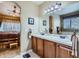 Bathroom featuring double sinks, wood cabinets, and an arched doorway leading to the main bedroom at 10968 Macon St, Commerce City, CO 80640