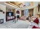 Comfortable living room featuring a cozy fireplace, plush sofas, and an elegant tray ceiling with fan at 10968 Macon St, Commerce City, CO 80640