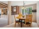 Bright dining area with a round wooden table, complemented by a large window with views of trees and a brick accent wall at 25808 Sunrise Ln, Golden, CO 80401