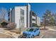 An exterior view of the condo building with gray siding and a blue car parked nearby at 14066 E Stanford Cir # H08, Aurora, CO 80015