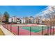 Community tennis courts are surrounded by mature trees with community buildings shown in the background at 14066 E Stanford Cir # H08, Aurora, CO 80015