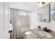 Well-lit bathroom featuring granite countertops, a black and white shower curtain, and white cabinets at 6725 Lionshead Pkwy, Lone Tree, CO 80124