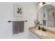 Well-lit bathroom with granite countertops, arched mirror, modern hardware, and decorative artwork at 6725 Lionshead Pkwy, Lone Tree, CO 80124