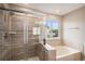 Modern bathroom featuring a tiled shower with glass door and a soaking tub with natural light at 1076 Switch Grass Dr, Castle Rock, CO 80109