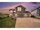 Exterior of a two-story home showcasing a three car garage, driveway, and landscaping with beautiful sunset colors at 1076 Switch Grass Dr, Castle Rock, CO 80109