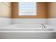 Close-up of a soaking tub with white tile surround and a glass block window for natural light at 17118 Knollside Ave, Parker, CO 80134