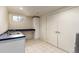 Bright laundry area featuring white cabinetry, countertop with sink, and tile floor at 105 S Dexter St, Denver, CO 80246