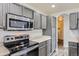 Modern kitchen features stainless steel appliances and sleek gray cabinets at 12507 Dexter Way, Thornton, CO 80241
