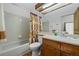 Bathroom featuring tub and shower combo, light tile, a wooden vanity, and shower curtain at 4020 E 94Th Ave # B, Thornton, CO 80229