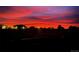 Night scene with vibrant red and pink sky above silhouette of houses and trees, showing peaceful community view at 196 W 8Th Ave, Byers, CO 80103