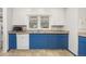 A kitchen featuring blue lower cabinets, white upper cabinets, and stainless steel appliances at 2921 S Holly Pl, Denver, CO 80222