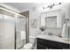 Bathroom with modern fixtures, shower with glass doors, vanity, and a decorative mirror with lighting at 1044 Rockhurst Dr # 207, Highlands Ranch, CO 80129