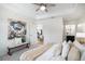 Bright bedroom featuring a ceiling fan, ensuite bathroom access, and decorative bench with artwork at 1044 Rockhurst Dr # 207, Highlands Ranch, CO 80129