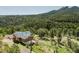 Aerial of a charming log cabin nestled among green trees with mountain views, offering privacy and serenity at 12135 Cochise Cir, Conifer, CO 80433