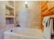 A cozy bathroom with a soaking tub and stone-tiled wall with log cabin features at 12135 Cochise Cir, Conifer, CO 80433