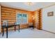 A bright bedroom with log walls, neutral carpet, and a window that showcases the outdoor scenery at 12135 Cochise Cir, Conifer, CO 80433