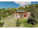 Log home featuring a large deck, a red garage door, and landscaping at 12135 Cochise Cir, Conifer, CO 80433