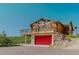 Log cabin with a spacious balcony above a red garage door, offering stunning views of the surrounding nature at 12135 Cochise Cir, Conifer, CO 80433