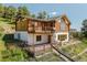 Exterior view of a log home with multiple decks, a landscaped yard, and stone accents at 12135 Cochise Cir, Conifer, CO 80433
