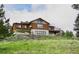Charming log home on a hillside with a deck, beautiful lawn, and lovely landscaping at 12135 Cochise Cir, Conifer, CO 80433