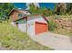 Side view of a garage featuring white stucco, a red garage door, and concrete driveway at 12135 Cochise Cir, Conifer, CO 80433