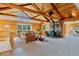 Rustic living room with log walls, vaulted ceilings, a stone fireplace, and abundant natural light at 12135 Cochise Cir, Conifer, CO 80433