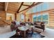 Bright living room featuring log walls, exposed beams, and large windows showcasing mountain views at 12135 Cochise Cir, Conifer, CO 80433