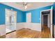 Bright blue bedroom with hardwood floors, chair railing, and access to the sunroom and hallway at 755 Newark St, Aurora, CO 80010