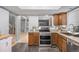 Open kitchen with stainless steel appliances, oak cabinets, granite counters, and a view into adjacent living spaces at 4028 S Atchison Way, Aurora, CO 80014