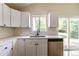 Bright kitchen featuring white cabinets, subway tile backsplash, stainless steel dishwasher, and double basin sink at 11524 Marshall Ct, Broomfield, CO 80020