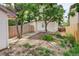 Cozy backyard featuring a wooden fence, trees, and a concrete path to the back door at 4720 S Bannock St, Englewood, CO 80110