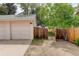 Detached garage with a wooden fence, gate and an adjacent gravel area at 4720 S Bannock St, Englewood, CO 80110