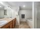 Bathroom with a dual sink vanity, large mirror, soaking tub, ceramic tile and a glass enclosed shower at 10818 Cimarron St # 206, Firestone, CO 80504
