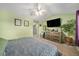 Cozy bedroom featuring light green walls, carpet, ceiling fan and a television mounted above a wooden dresser at 10818 Cimarron St # 206, Firestone, CO 80504