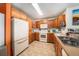 Functional kitchen with oak cabinets, white appliances, and ample counter space at 10818 Cimarron St # 206, Firestone, CO 80504