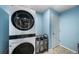 Well-lit laundry room with blue walls and modern, stacked washer and dryer at 10818 Cimarron St # 206, Firestone, CO 80504