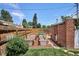 Backyard showcasing raised garden beds, lush greenery, a brick-lined pathway, and wooden fencing for privacy at 3622 Lowell Blvd, Denver, CO 80211